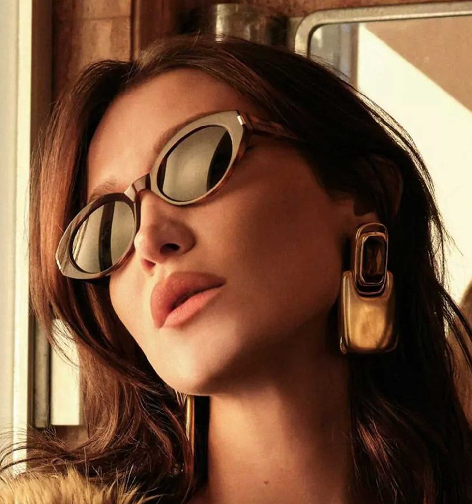 Bella Hadid wearing Saint Laurent cat-eye sunglasses and oversized gold earrings