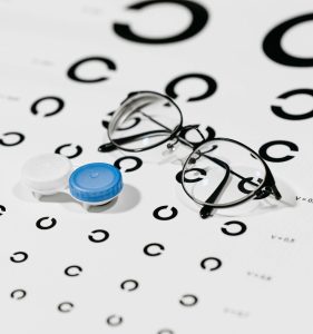 A contact lens case and eyeglasses on an astigmatism eye chart