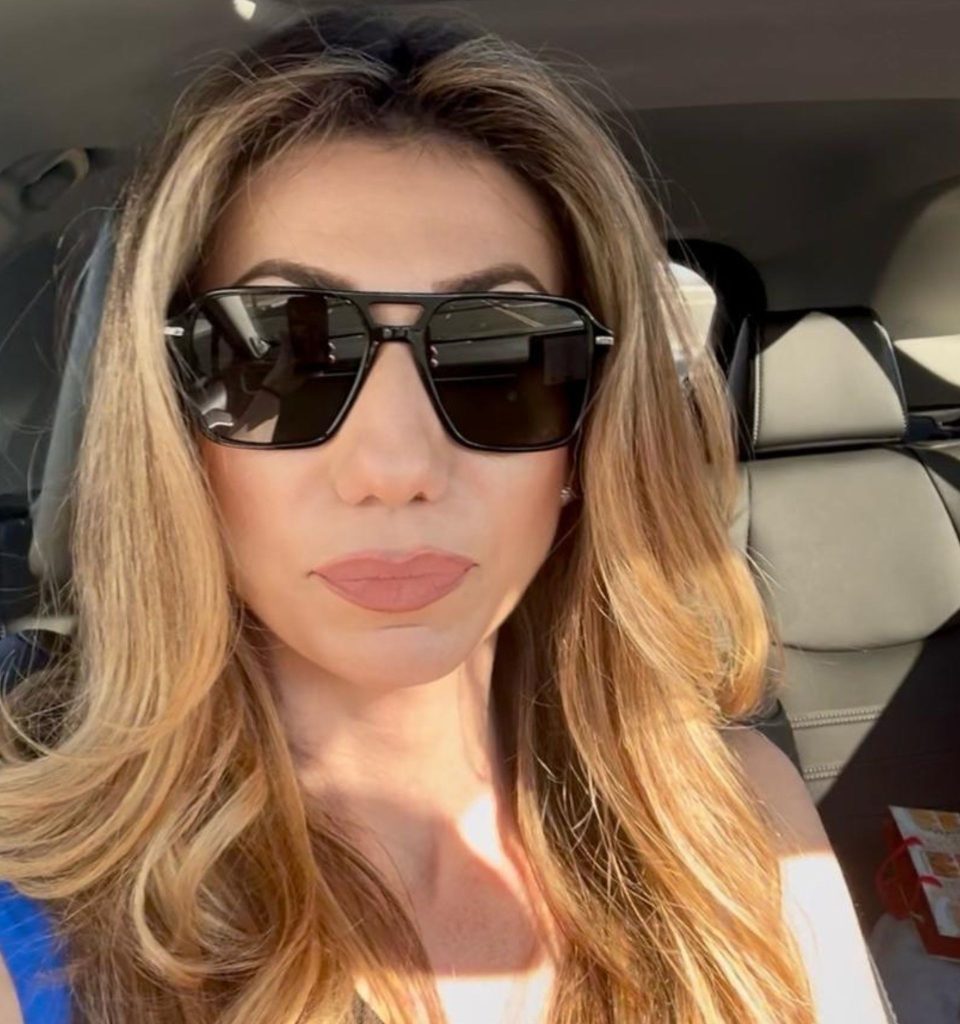 An EZContacts customer named Carmen wearing her new Miu Miu 11ZS oversized black sunglasses