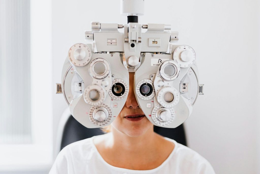 A woman sitting behind a phoropter during an eye examination