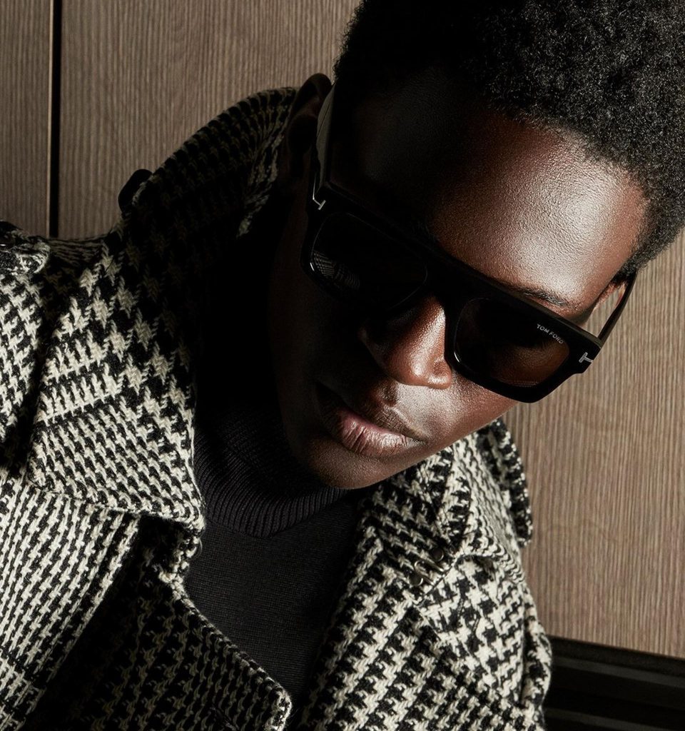 A stylish man wearing black Tom Ford sunglasses with a houndstooth coat