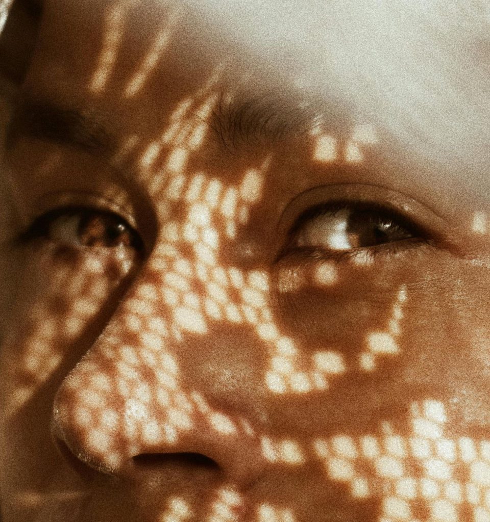 Close-up view of the upper half of a woman’s face as she is enveloped in sunlight
