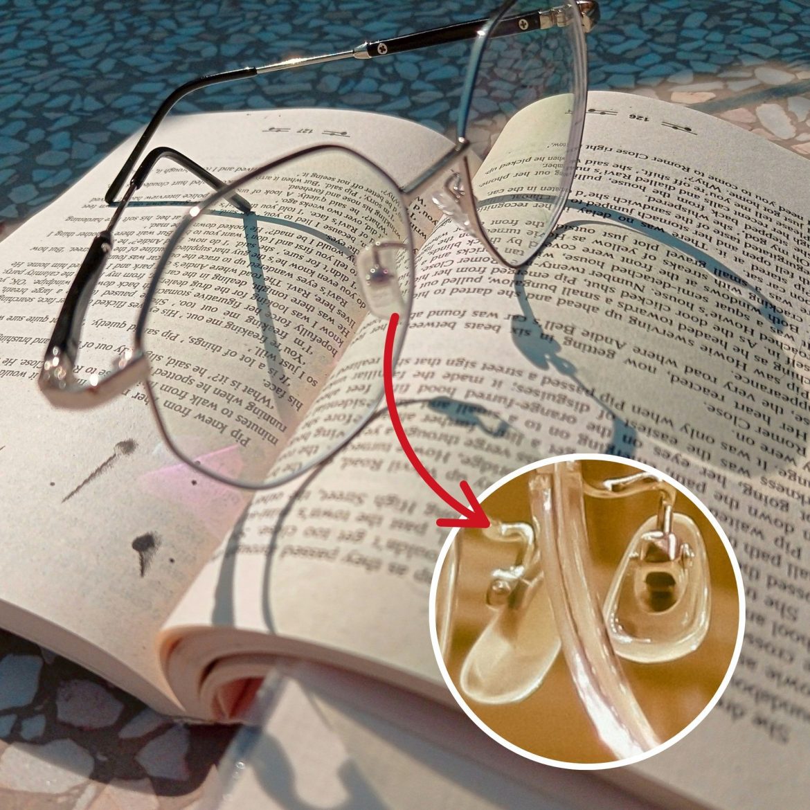 Metal-framed eyeglasses, with clear nose pads, on top of an open book