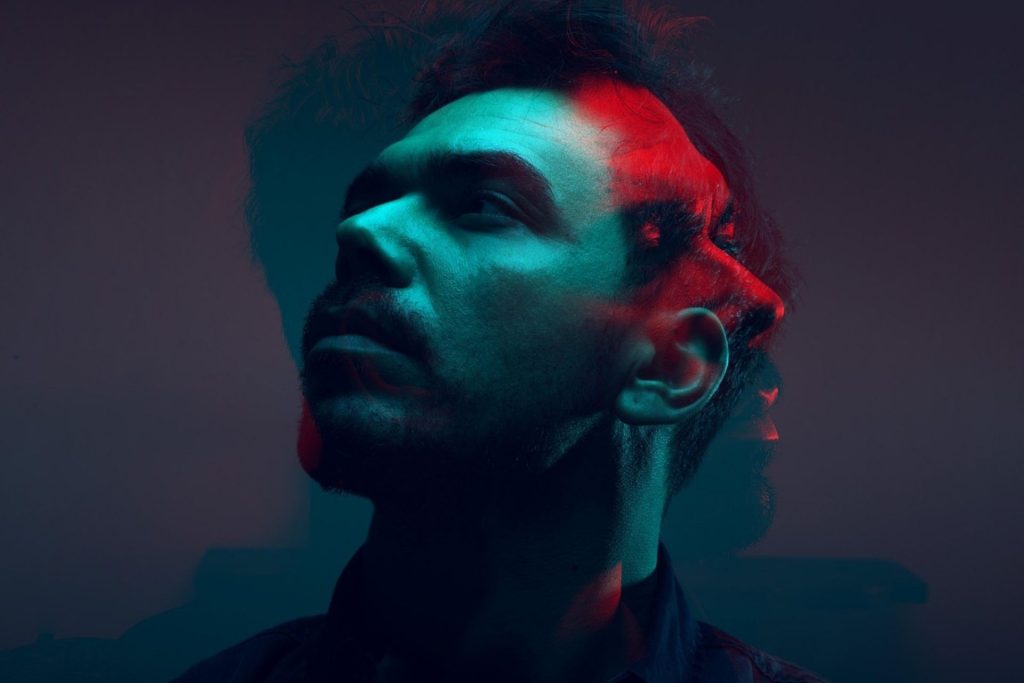 Double-exposed image of a man’s face in hues of blue and red