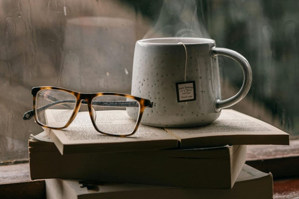 A cup of tea and glasses on a stack of books
