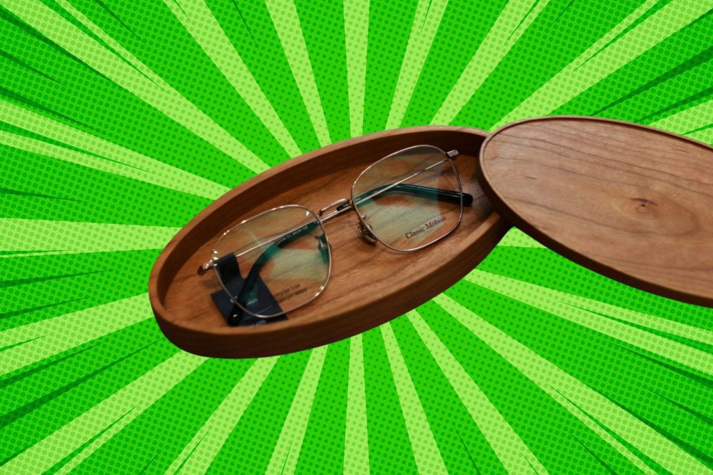 A pair of square, metal-rimmed eyeglasses in a wooden holder