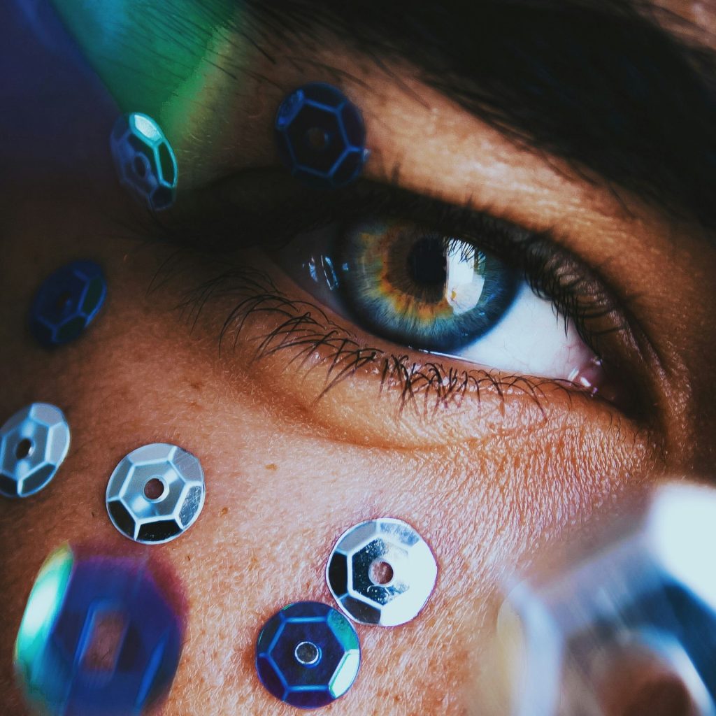 Close-up of a blue eye surrounded by blue metallic sequins