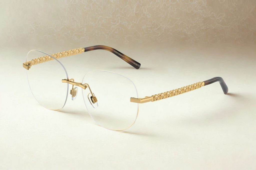 Curved, rimless women’s glasses featuring a repetitive, gold “DG” logo along the arms and tortoiseshell coated temple tips
