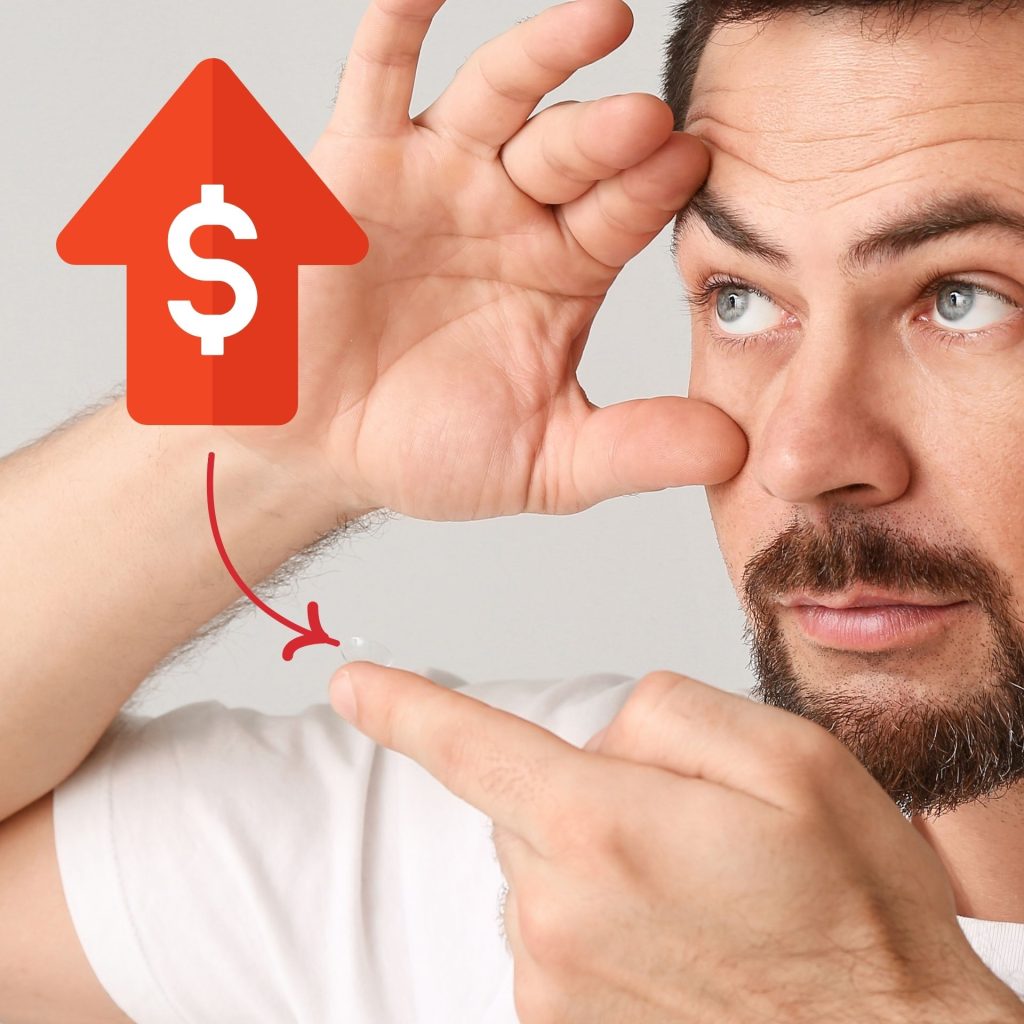 A price increase label points to a contact lens on the tip of a man's finger