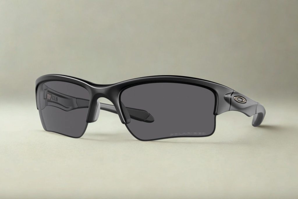 Black half-rim sunglasses with grey lenses and the Oakley logo near the hinges