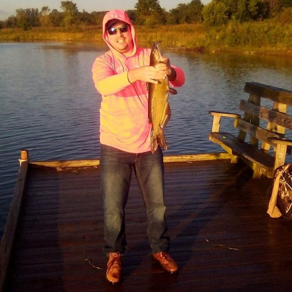 Man holds fish and wears sunglasses