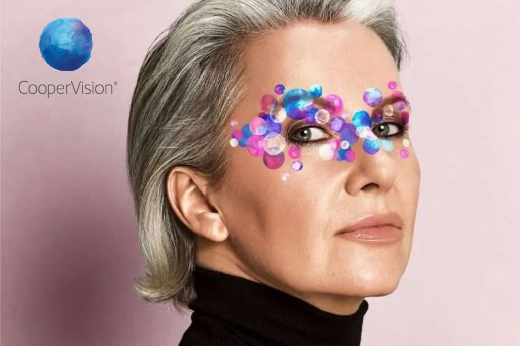 A mature woman, with colorful dots surrounding her eyes, representing CooperVision