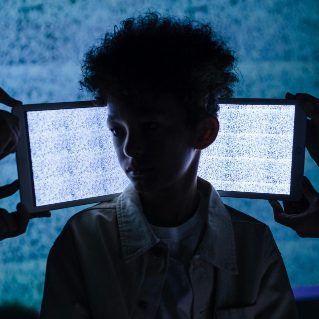 A young boy with two tablet screens behind him