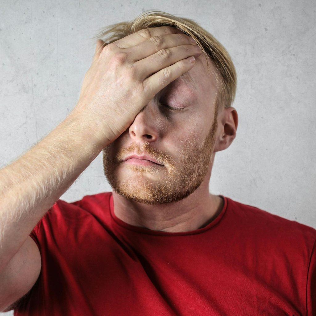 Man touches his head with eyes closed