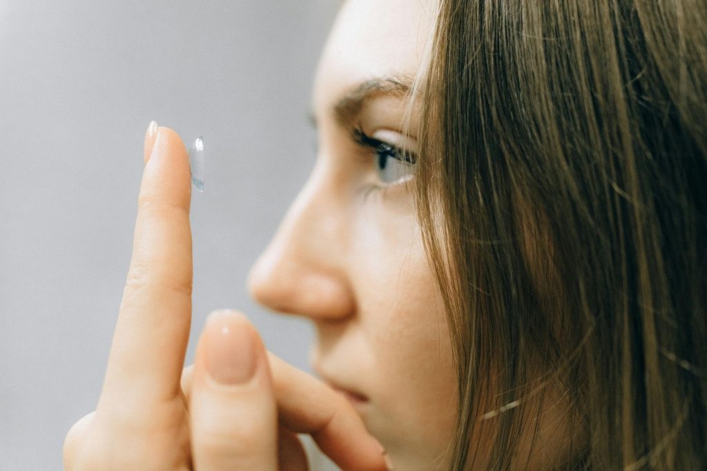 A woman holding a contact lens up to her eye