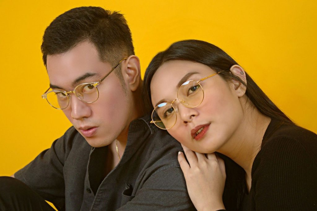 A couple getting cozy while wearing round, unisex glasses