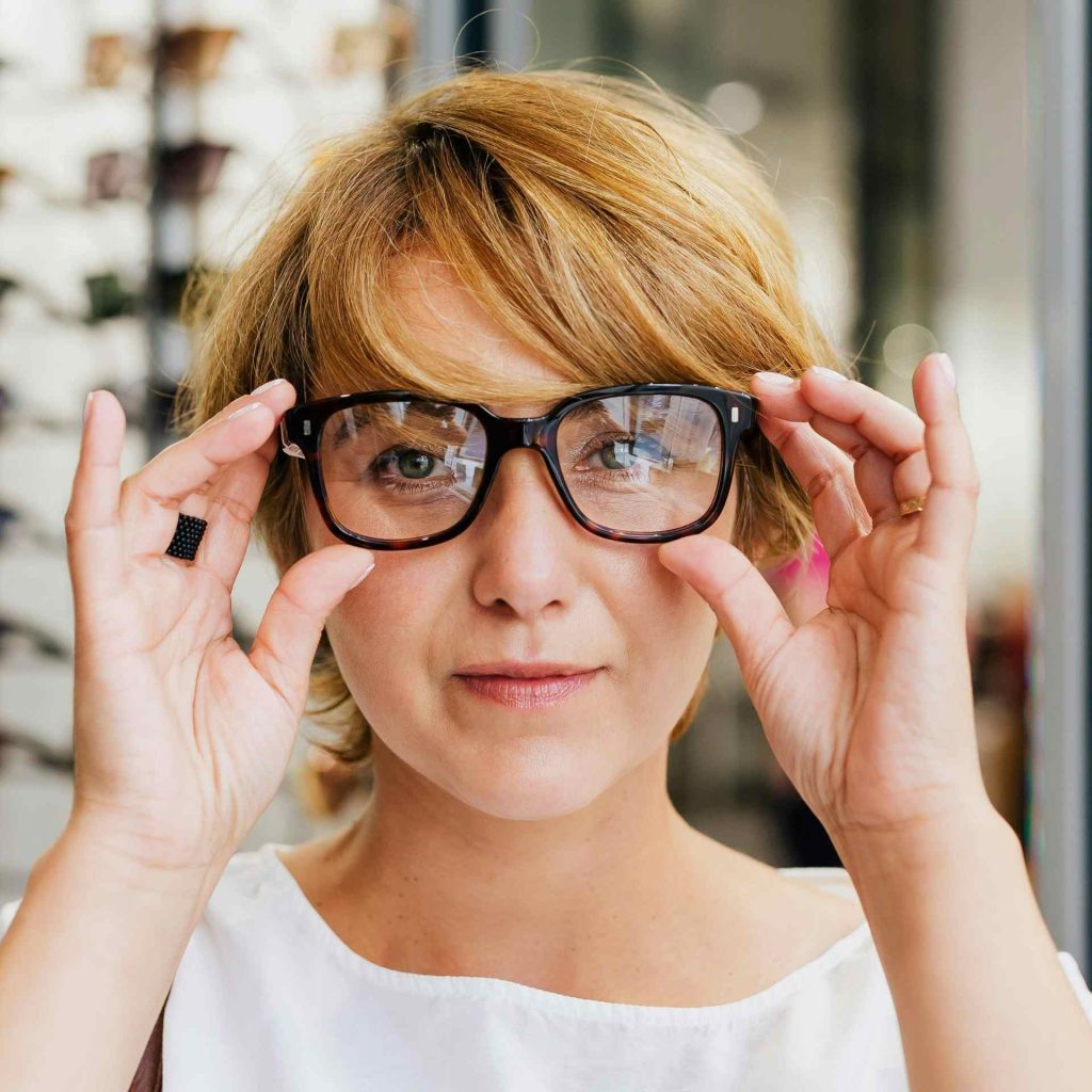 A woman trying on glasses in a local eyewear retail store