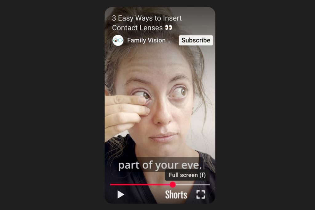 Woman placing a contact in her eye with one hand