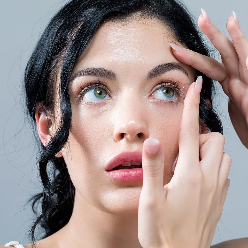 A woman with long nails trying to remove her contact lenses
