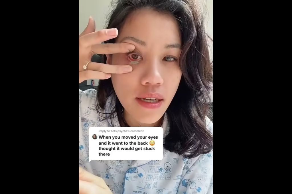 An influencer demonstrating how to use a no-touch method to remove contacts with long nails