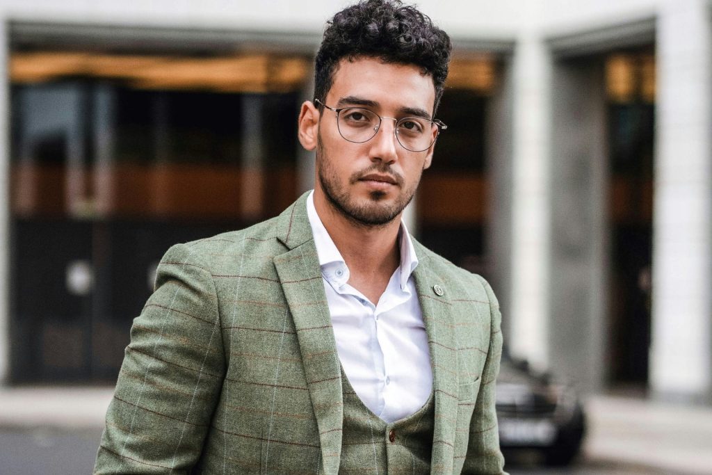 Man wearing a green suit and round eyeglasses