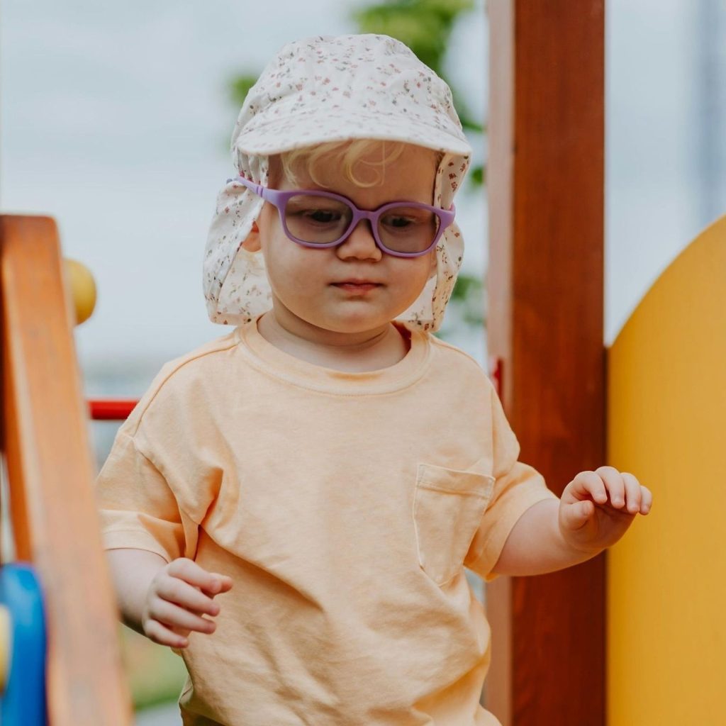 A toddler with purple glasses plays at a playground