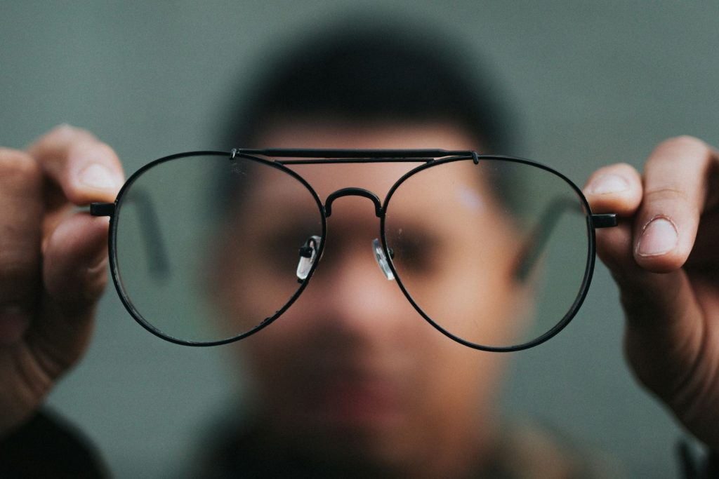 Man holding aviator eyeglasses featuring black metal frames