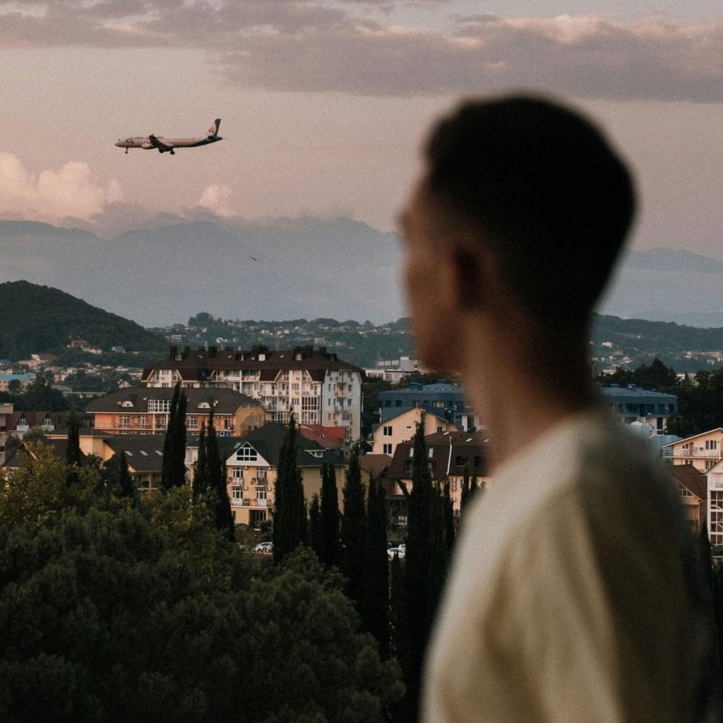 Blurred foreground of a man standing, clear background view of a city and plane
