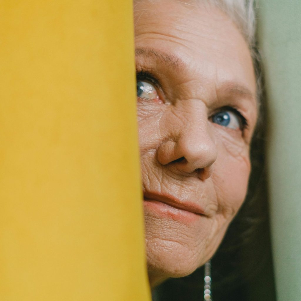 Elderly woman looking around corner