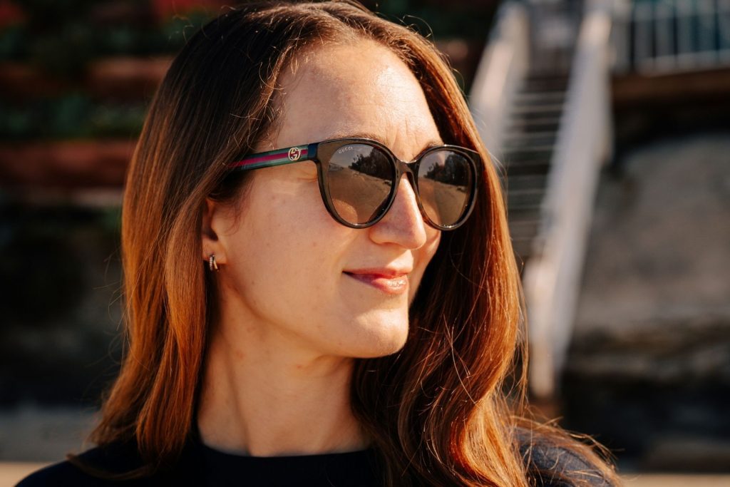 Woman wearing Gucci sunglasses featuring the Gucci logo on the arm