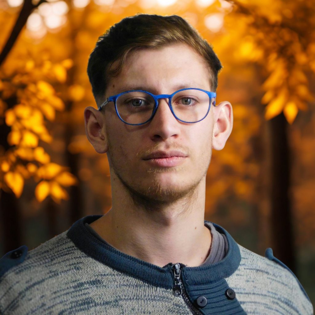 Man wearing blue round eyeglasses and a blue sweater