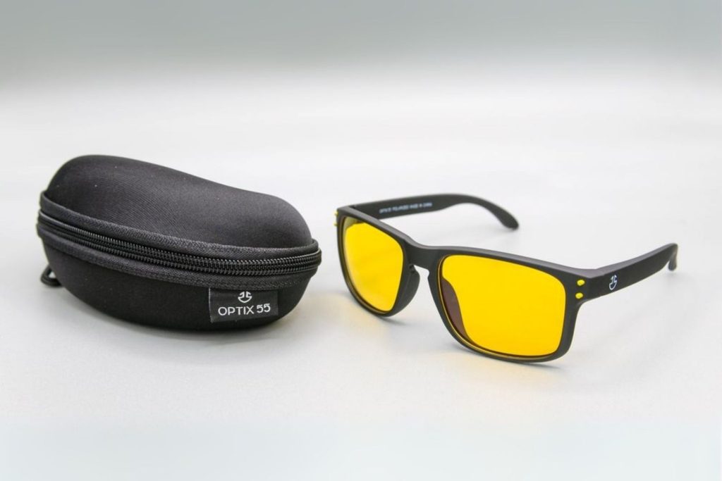 Black frames with yellow-tinted lenses, next to a glasses case