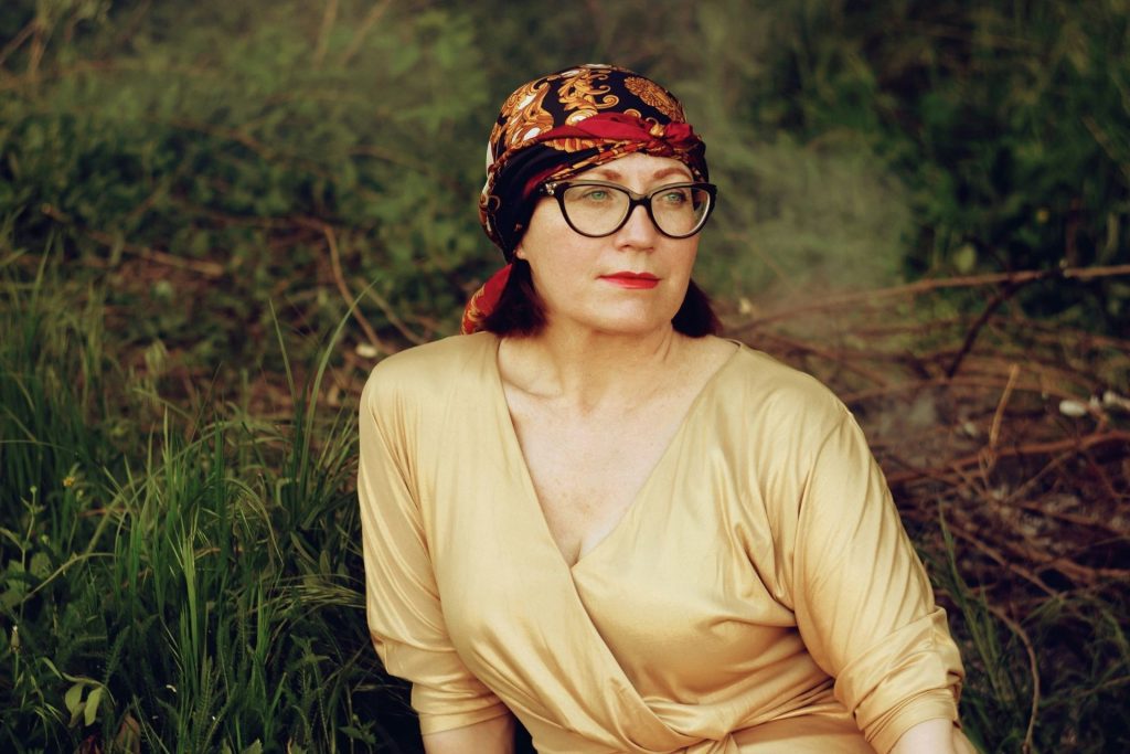 Woman wearing a gold dress and cat-eye tortoiseshell glasses