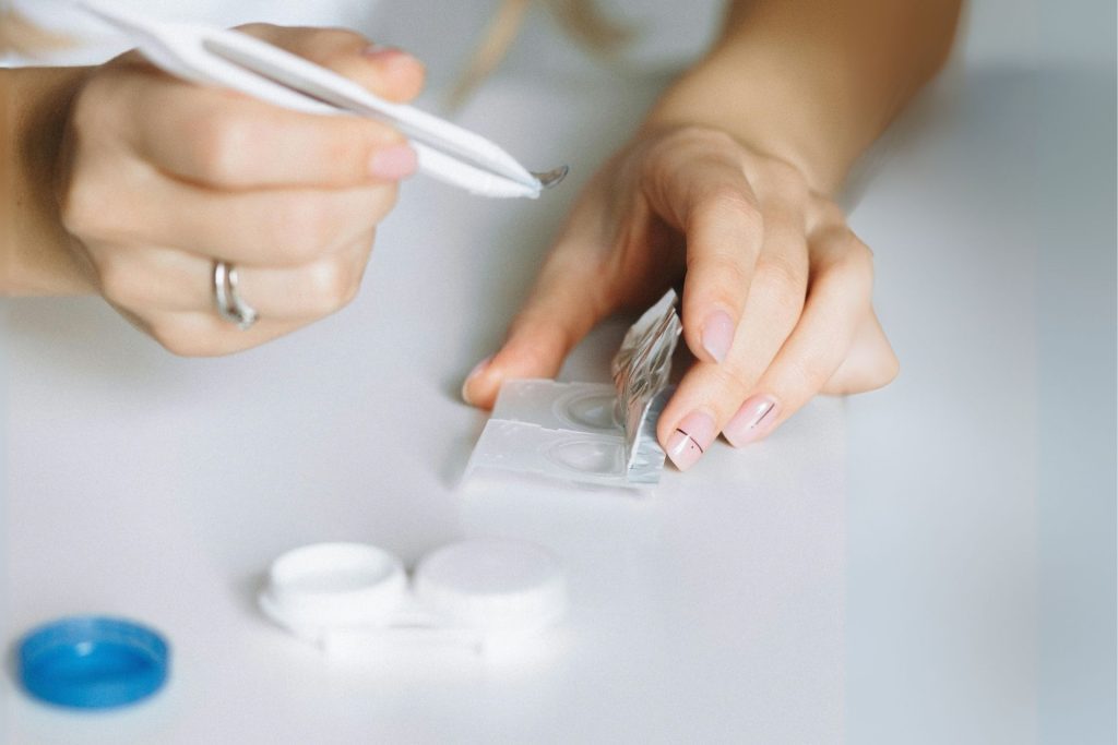 A person opens a new tab of contact lenses and prepares to wear them