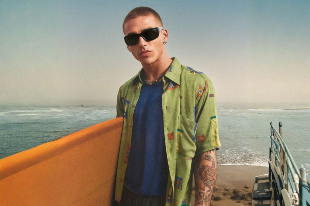 Surfer wearing gray Arnette sunglasses on the beach