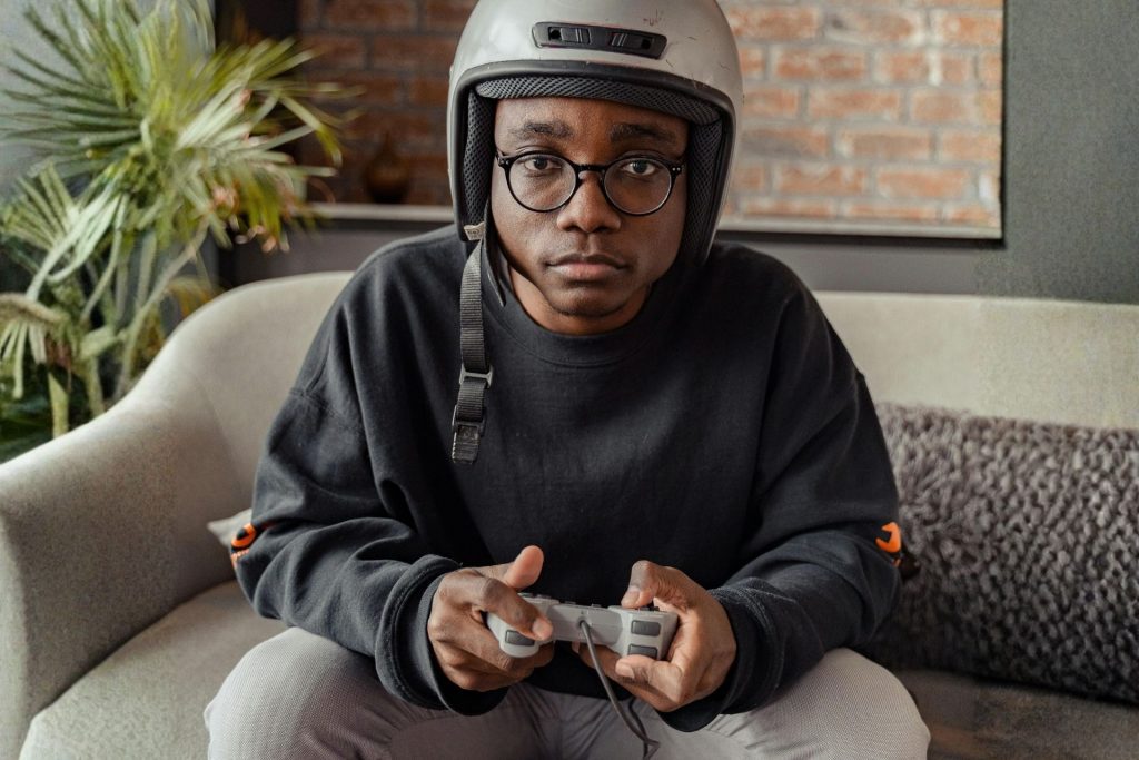 Man wearing glasses and a helmet, using a gaming console