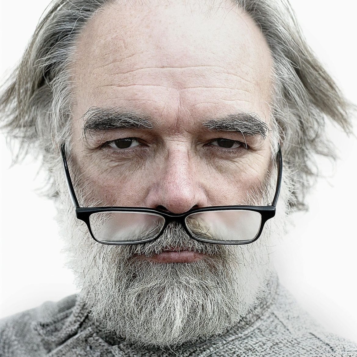 Old man with black glasses brought down to his nose