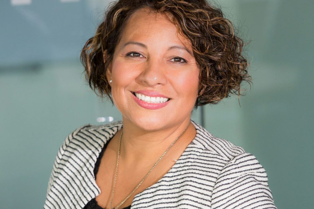 Woman smiling wearing a striped blazer and black blouse