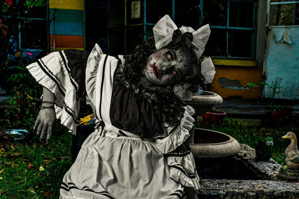 Person in a scary doll costume on the ground, splayed like a doll