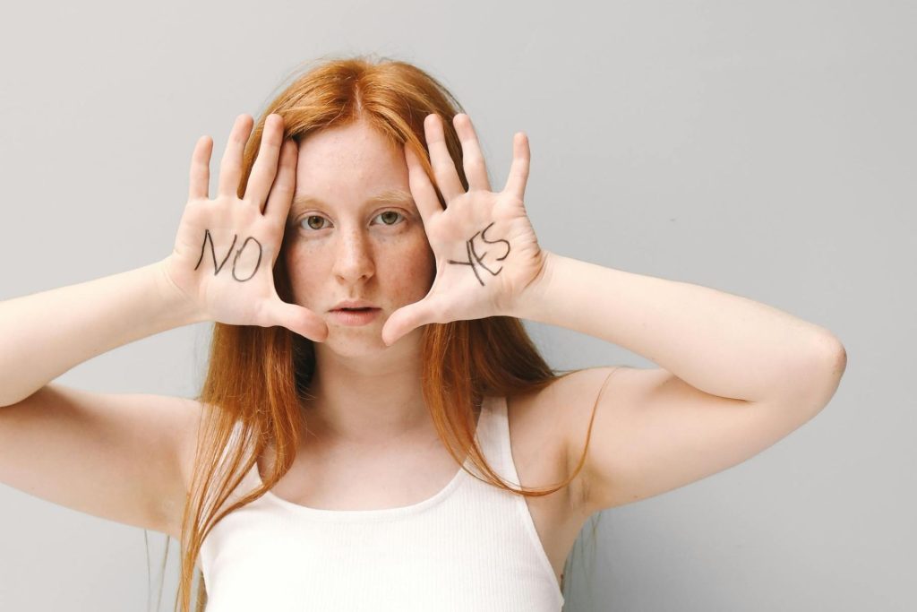 Woman in a white tank top, open palms with ‘yes’ and ‘no’ near her face