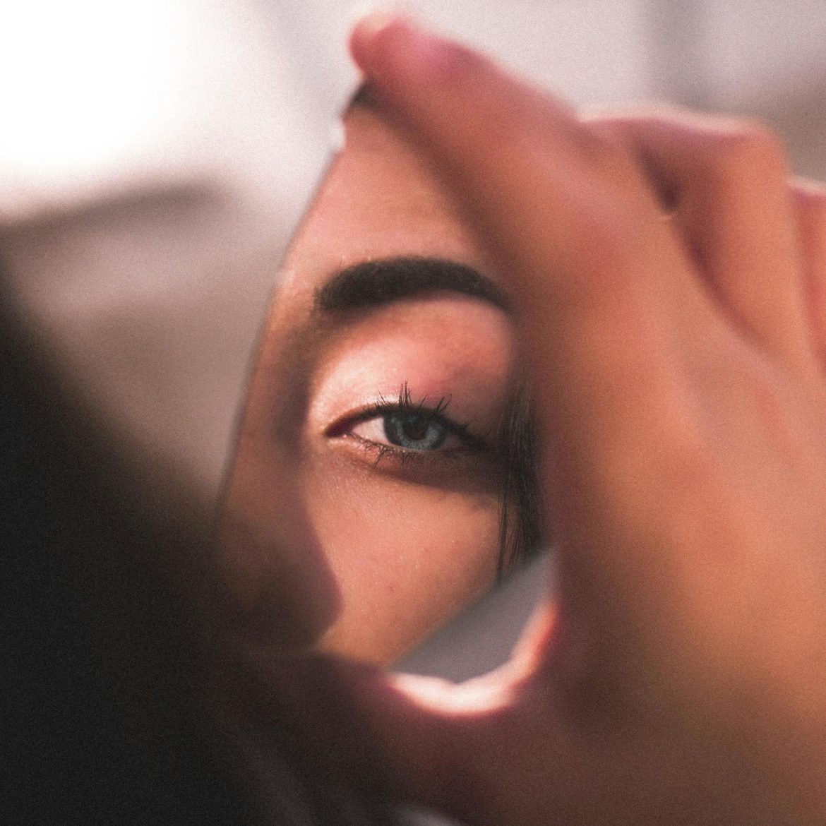A woman’s eye reflected in a broken mirror.