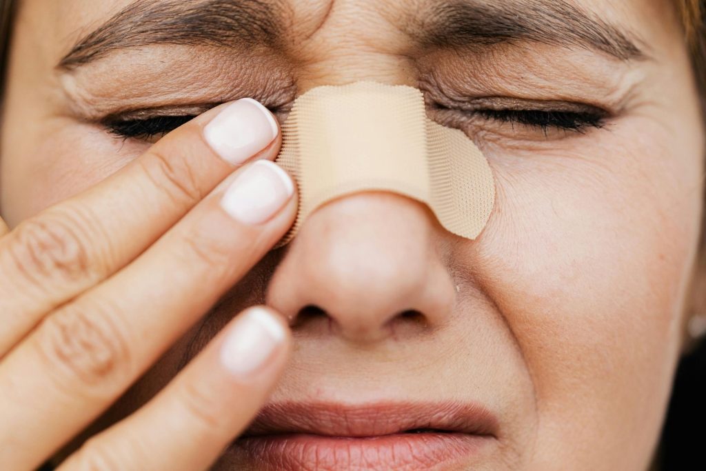 Woman with bandaged nose and hurting eyes