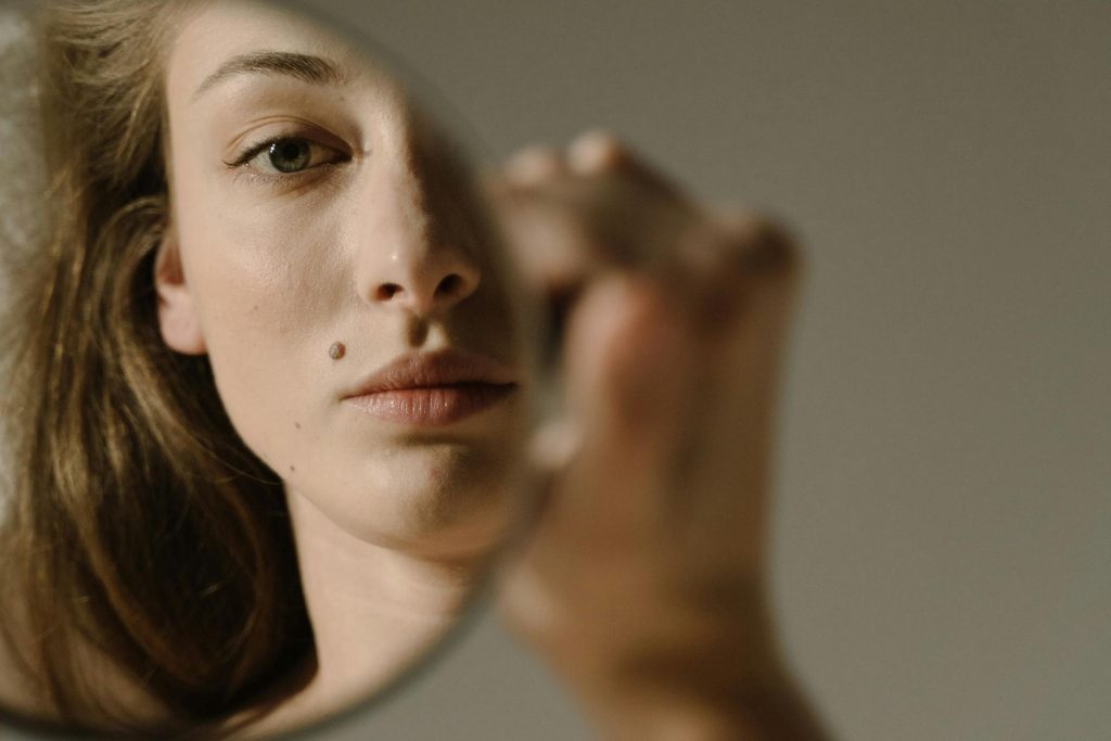 Woman looks at her reflection in a mirror