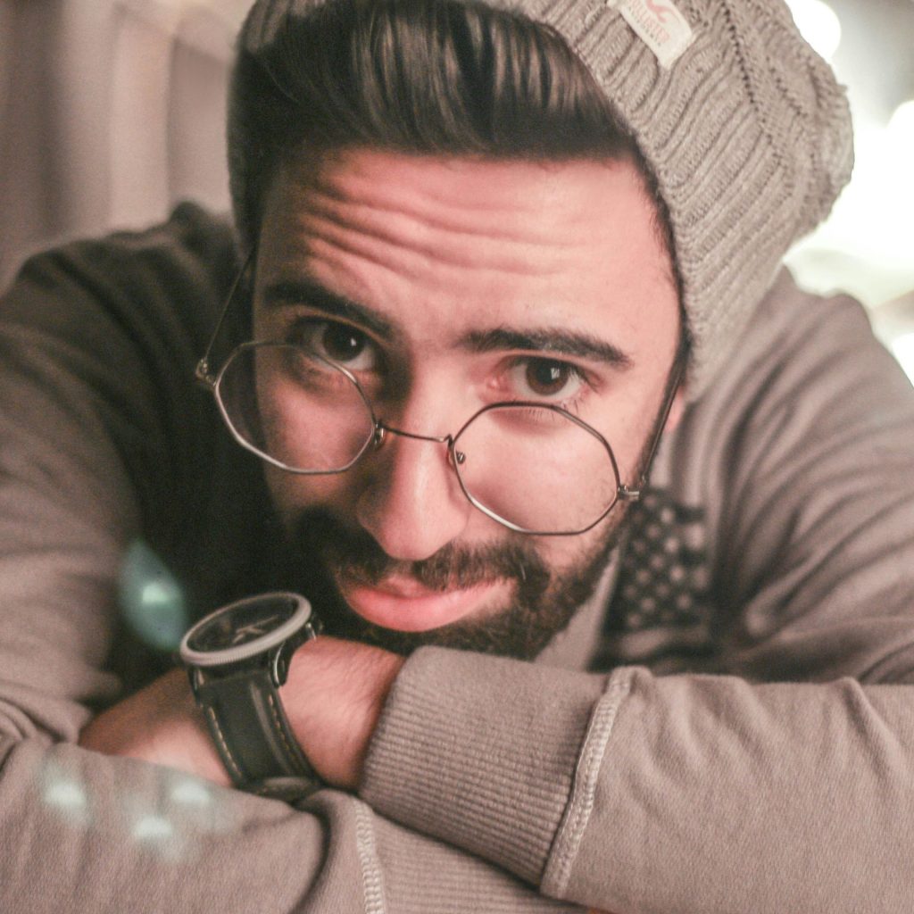 Man wearing wire-rimmed glasses, a gray beanie, and a jacket