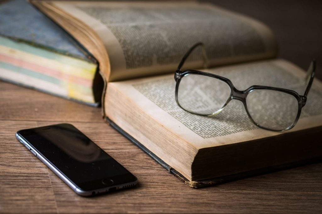 Glasses sitting on a book next to a smartphone