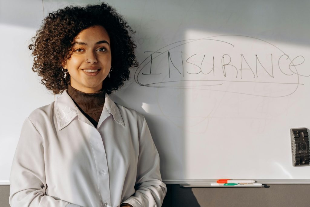 A woman standing in front of a white board with Insurance written on it