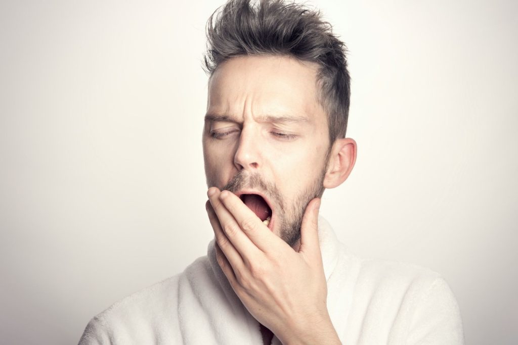Man Yawns and Covers Mouth
