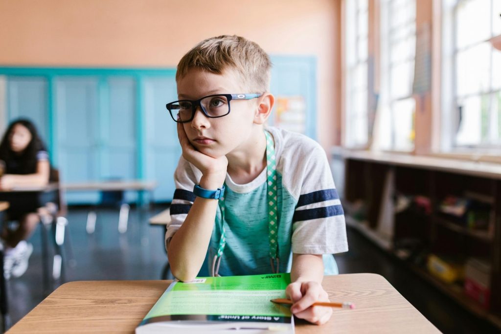 A child wearing eyeglasses sits at his desk