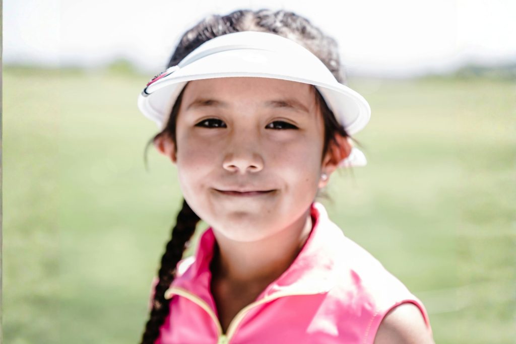 A girl wearing a visor and pink zip-up vest