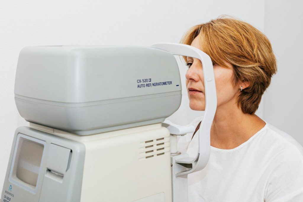 A woman sits behind a keratometer